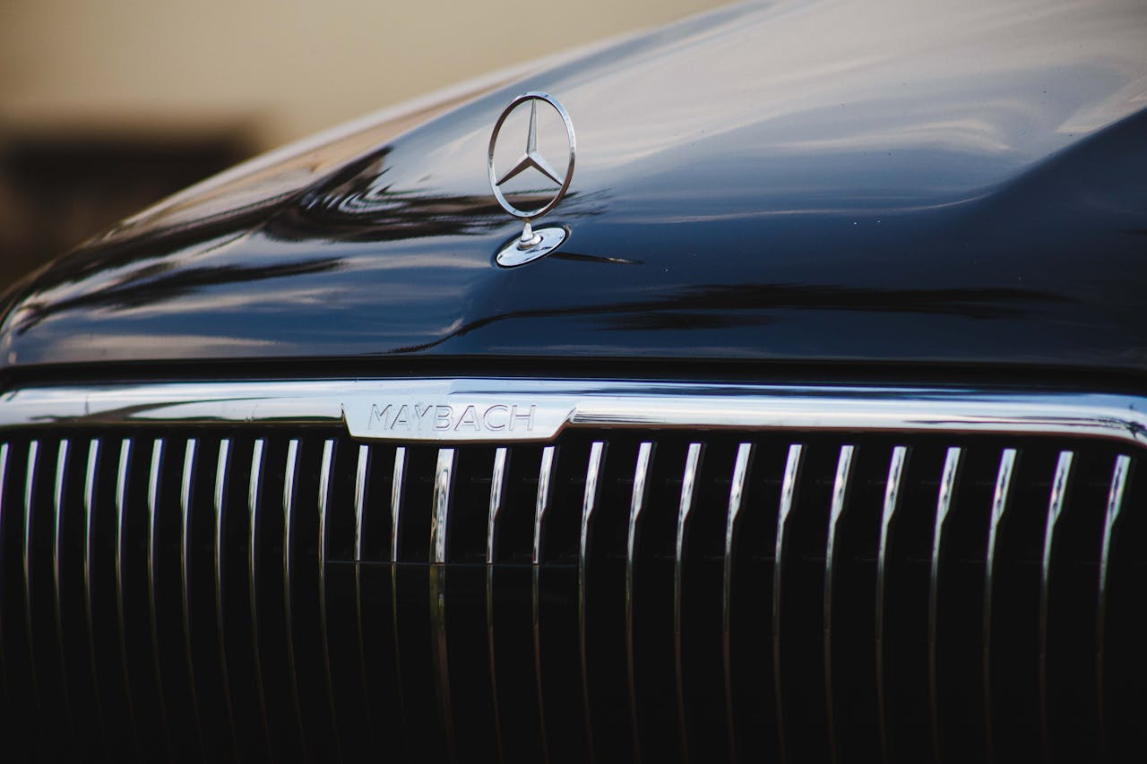 who-we-are-03 Detailed view of a luxury car's grille with brand emblem, reflecting elegance and sophistication.