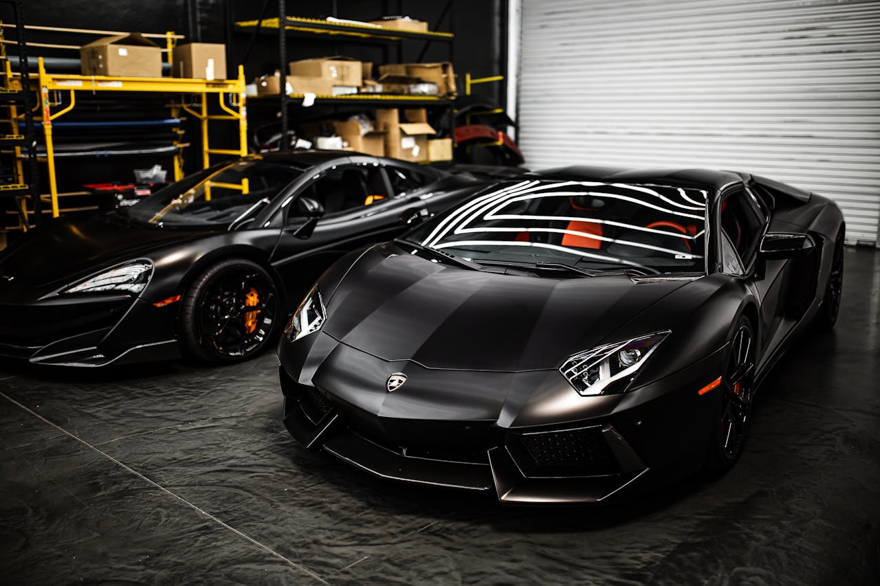 who-we-are-02 Sleek black sports cars parked in an industrial garage with modern design features.